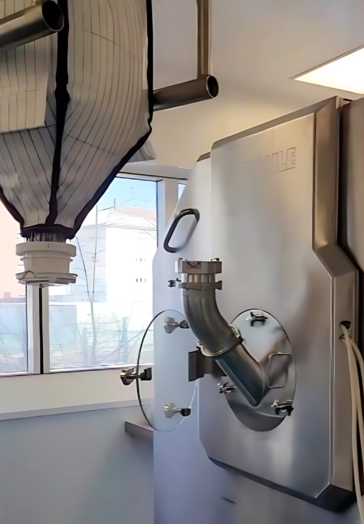 ACUBE DL Einwegsystem-Containment-System neben Tablettenbeschichtungsanlage für Pharmazeutika positioniert